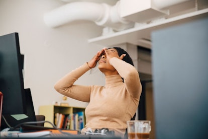 Woman desperately holding her head tired in front of the computer at her toxic job    