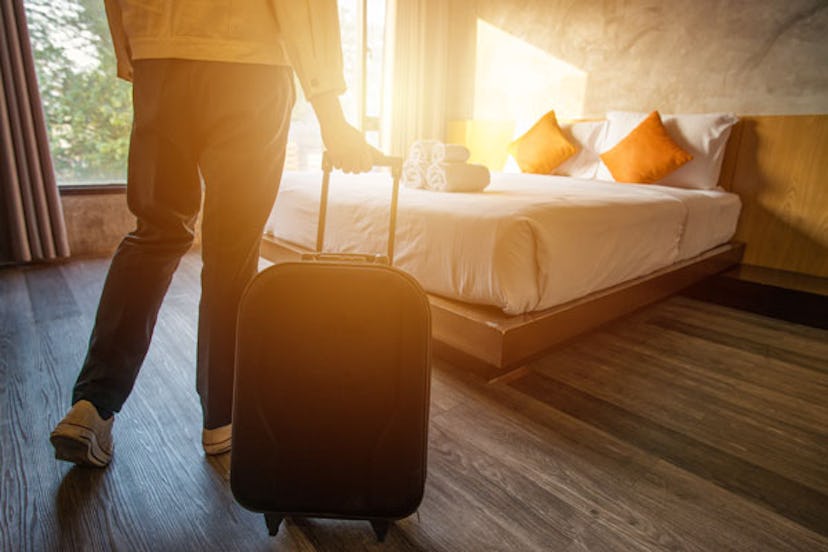 A person entering a hotel room and dragging their suitcase alone to combat the mom burnout