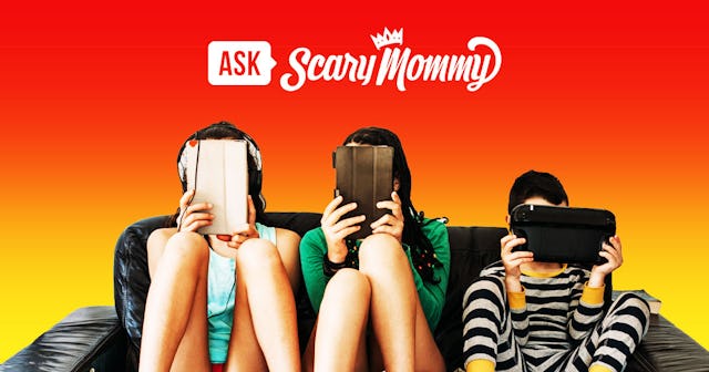 Two teenagers and a younger boy sitting on the sofa, all looking at their tablets.