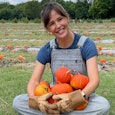 Jennifer Garner sitting in a pumpkin field, holding a bunch of pumpkins in her hands and smiling