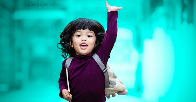  Kindergarten student with her backpack on smiling with one arm raised