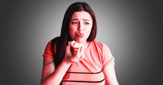 A woman cautiously eating a cookie 