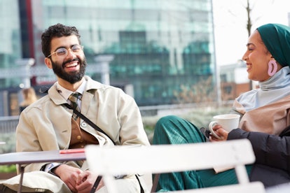 A male and a female sharing laughter during their conversation.