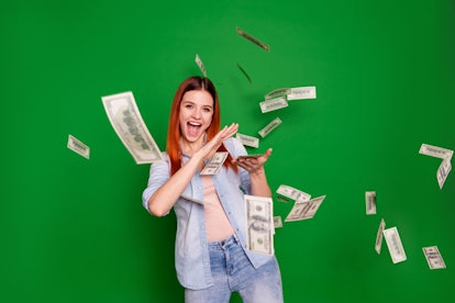 Red-haired girl smiling while throwing money in the air 
