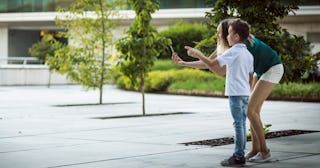 Young woman and child playing game on phone — games like Pokemon Go.