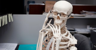 Funny skeleton sitting at desk — skeleton jokes and puns.
