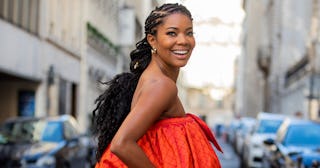 Gabrielle Union smiling in an orange sleeveless dress and walking