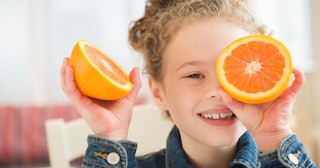 Girl holding orange and laughing — orange puns and jokes.