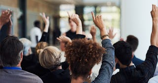People sitting at alecture and asking for help by raising their hands