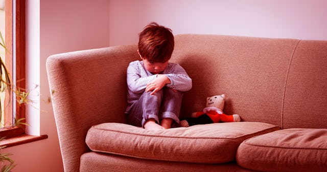A toddler boy sitting in a corner of a couch because he was smacked