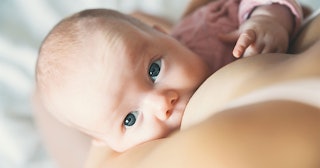 A closeup of a green-eyed baby during breastfeeding