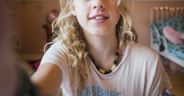 13-year-old blonde girl setting up a camera for a selfie