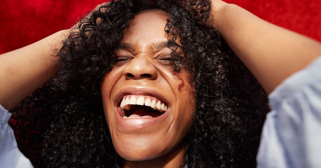 Woman with curly hair laughing at gross stuff with hands on her head