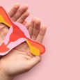 Hands holding paper cutout of a uterus 