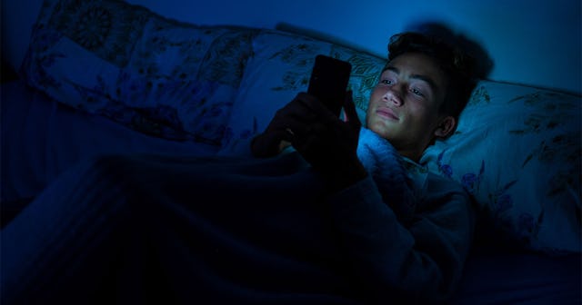 Boy surfing on his phone watching social media in the dark