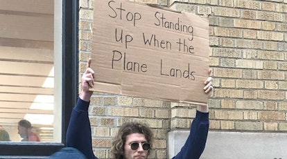 Dude with a sign "Stop standing up when the plane lands"