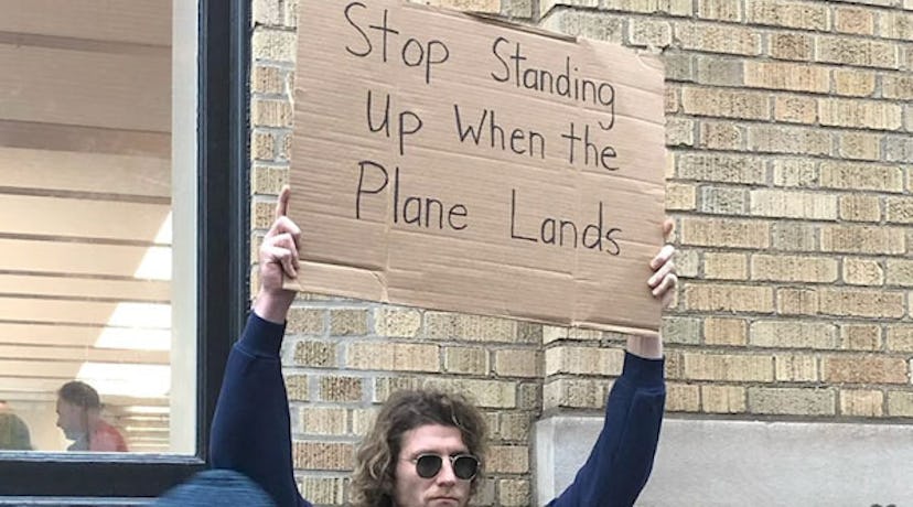 Dude with a sign "Stop standing up when the plane lands"