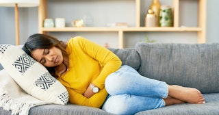 Woman clutching stomach — positions to help period cramps