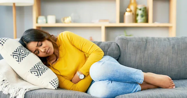 Woman clutching stomach — positions to help period cramps
