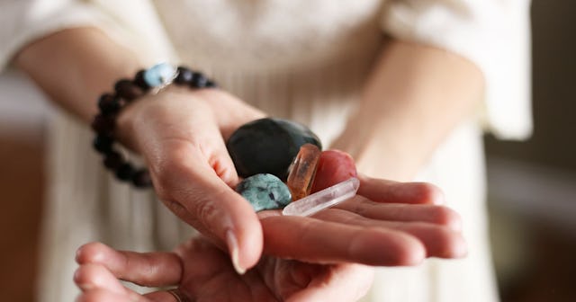 A woman holding various crystals in her hand