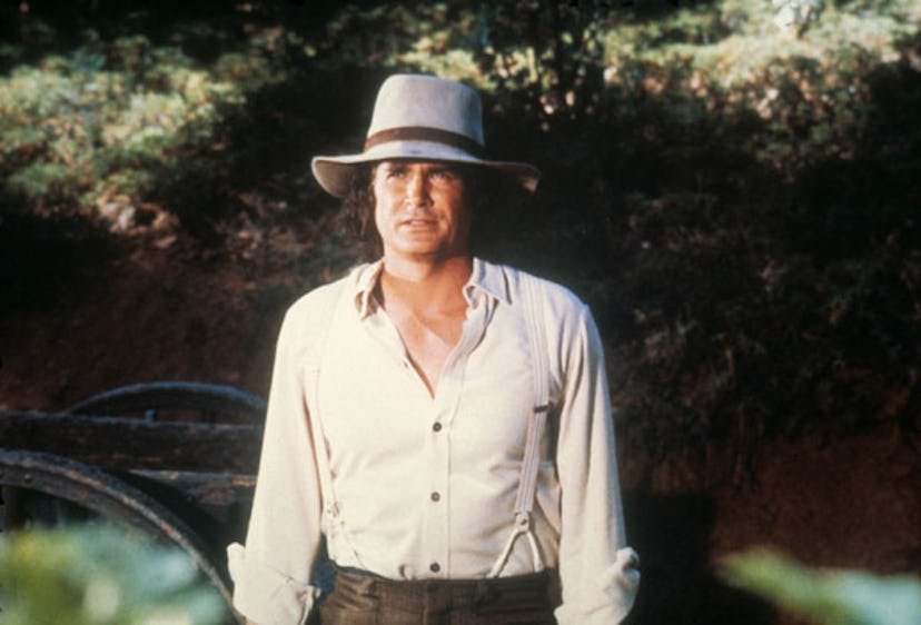 Michael Landon in a white shirt and a gray hat next to a river in the movie 'Little House on the Pra...