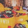 Huge amount of Halloween candy spread around and inside plastic pumpkins