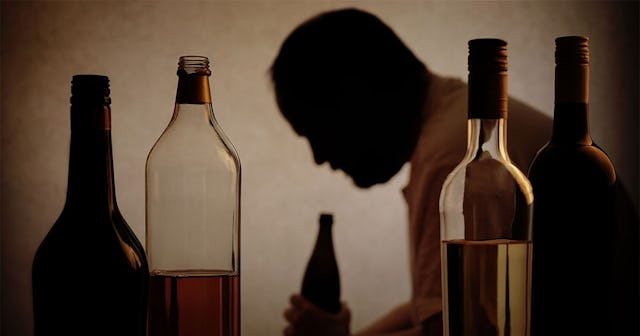 Alcoholic partner sitting in the room surrounded by bottles 
