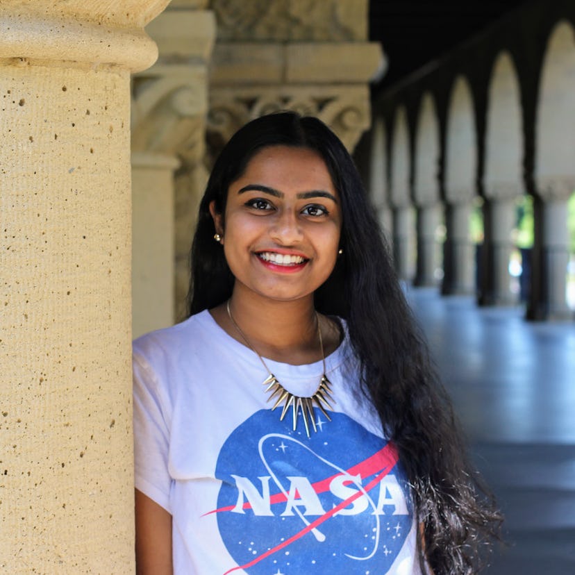 Akshaya Dinesh wearing a necklace and NASA shirt smiling from ear to ear.
