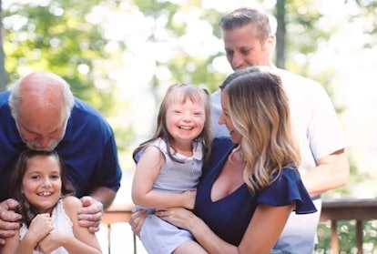 Girl with Down syndrome posing for a family photo with her parents, sister and grandfather 