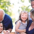 Girl with Down syndrome posing for a family photo with her parents, sister and grandfather 