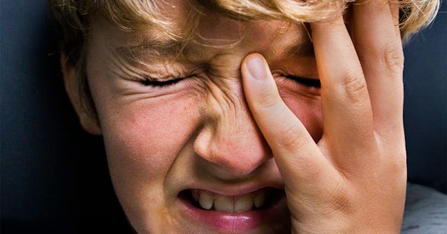 A child that is going through an emotional abuse desperately holding his head and crying