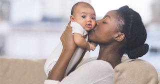 A Woman Kissing Her Baby With On The Cheek