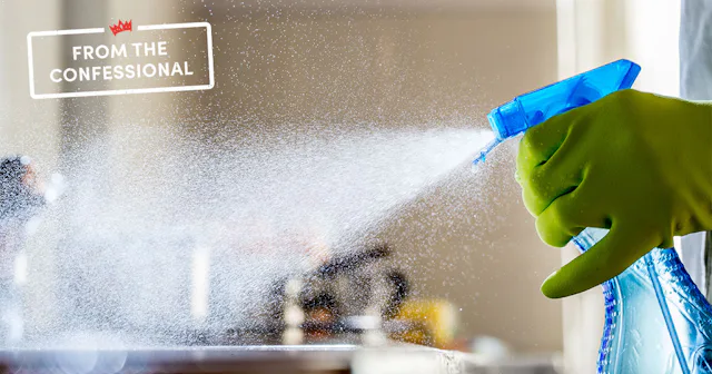 Woman cleaning and dispensing a cleaning supply out of a spray bottle wearing yellow rubber gloves