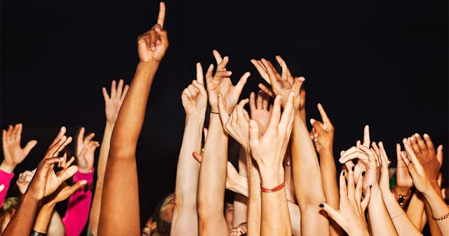 A Crowd Of People Holding Their Hands In The Air