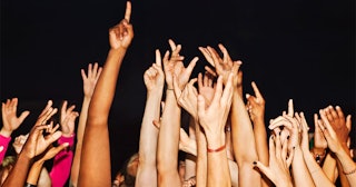 A Crowd Of People Holding Their Hands In The Air