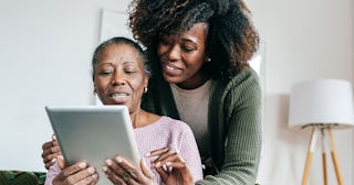 Daughter explaining to her elderly mother with dementia how to use a smart device