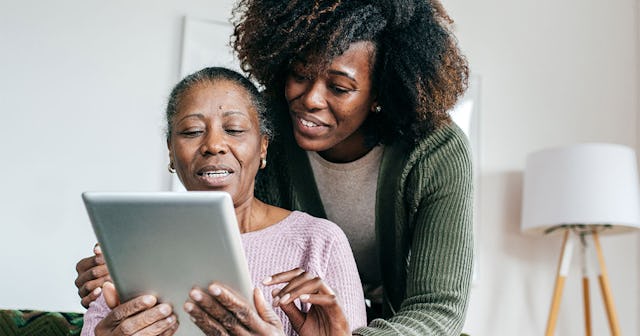 Daughter explaining to her elderly mother with dementia how to use a smart device