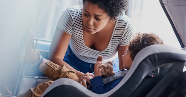 Woman checking on child in car — car sickness kids.