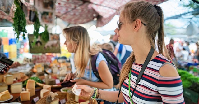 Mother and daughter at a farmers market on vacation — traveling with money.