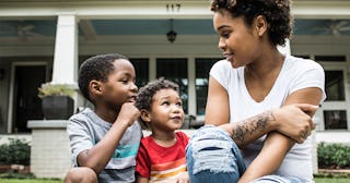 A mother wearing a white shirt with a tattoo on her arm talking with both of her sons