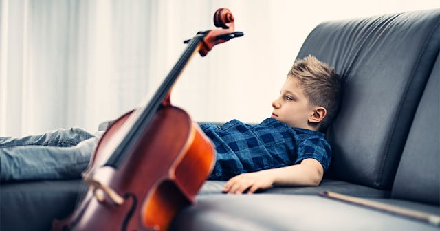 A boy lying on a couch next to a violin 