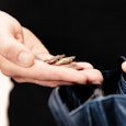 A Person Holding Their Wallet And Change In Their Hand