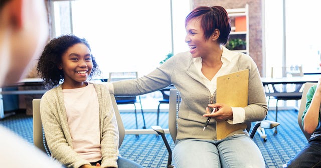 A counselor during a therapy session talking to a girl who is smiling