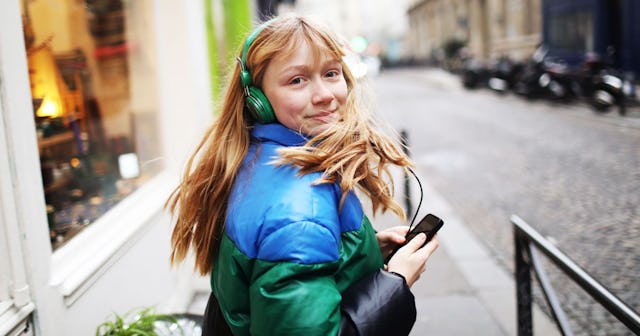Teenage girl with long hair in a winter jacket with headphones on