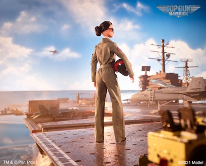 A "Top Gun Maverick" edition of a Barbie doll standing on a carrier in a military suit and helmet.