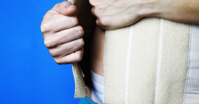 Woman putting her postpartum belly wrap on her belly