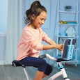 A young girl driving a peloton-like bike for kids at home