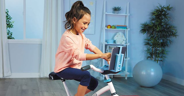A young girl driving a peloton-like bike for kids at home
