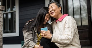 An Overemotional mother and her daughter sitting on a porch while laughing and hugging