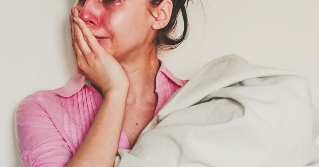 A crying woman in a pink shirt suffering from postpartum depression